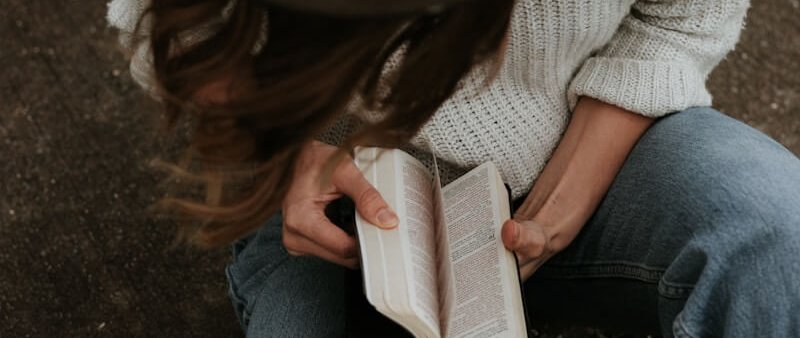 woman sitting on ground while opening book